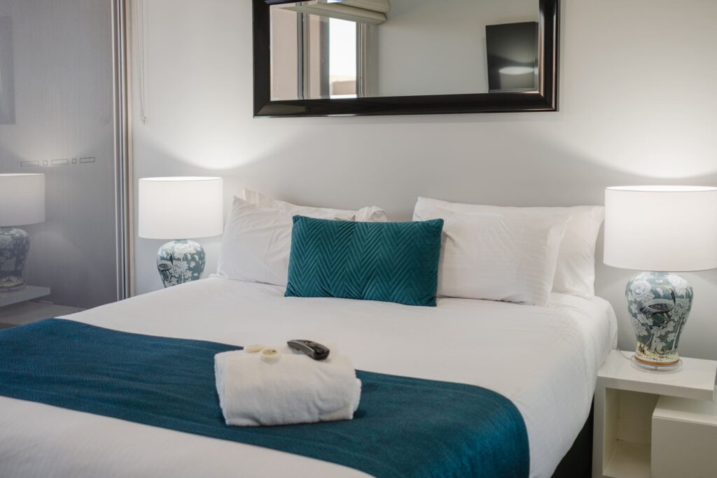 Main bedroom in prestige two bedroom room 703 at Honeysuckle Apartments with teal accents.