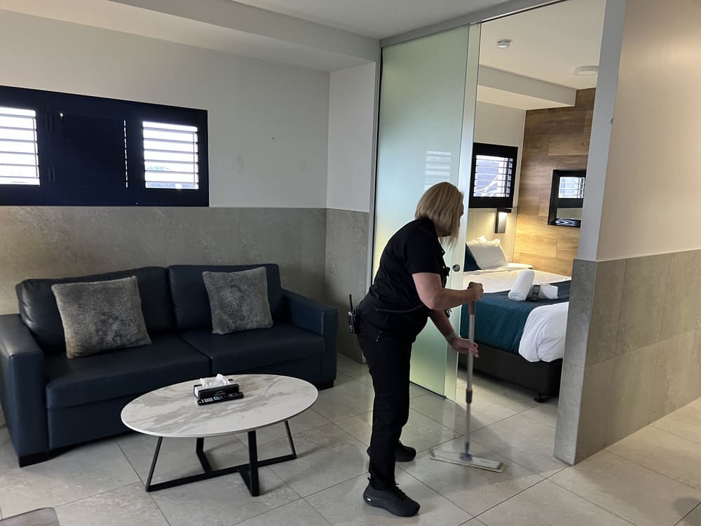 Cleaning staff mopping tiled floor in serviced apartment lounge at Honeysuckle Executive Apartments Newcastle
