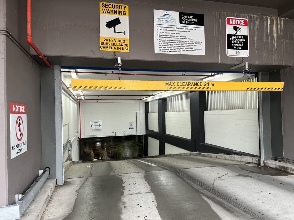 Carpark entrance at Honeysuckle Executive Apartments with security signs, clearance bar and no pedestrian access
