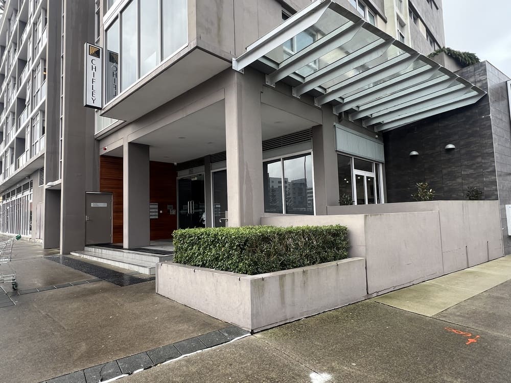 Main entrance to Honeysuckle Executive Apartments with glass awning and Chifley signage on facade