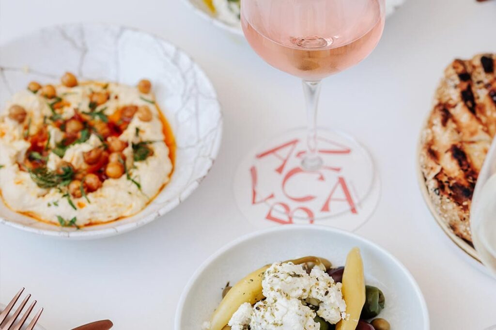 Mediterranean mezze with hummus, olives, flatbread and wine near Honeysuckle Apartments.