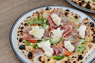 Gourmet pizza with prosciutto, ricotta, and rocket near Honeysuckle Apartments Newcastle.